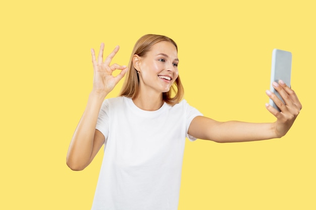 Caucasian young woman's half-length portrait on yellow studio