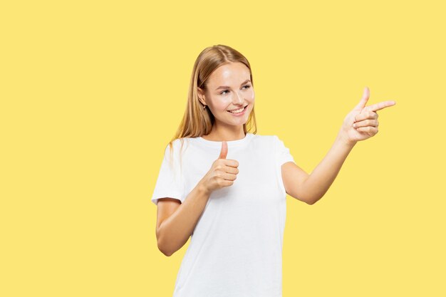 Caucasian young woman's half-length portrait on yellow studio