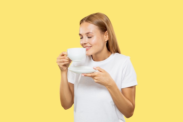 Free photo caucasian young woman's half-length portrait on yellow studio