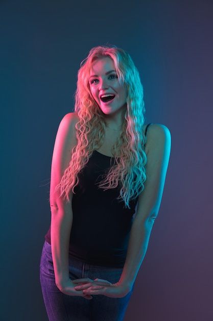 Caucasian young woman's portrait on gradient background in neon light. Beautiful female model with unusual look. Concept of human emotions, facial expression, sales, ad. Smiling cute.