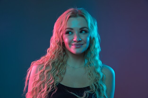 Caucasian young woman's portrait on gradient background in neon light. Beautiful female model with unusual look. Concept of human emotions, facial expression, sales, ad. Smiling cute.