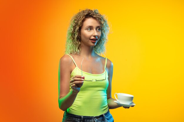 Caucasian young woman's portrait on gradient studio in neon