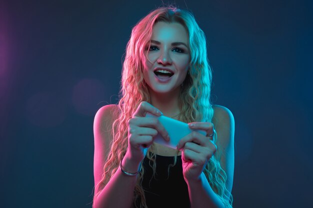 Caucasian young woman's portrait on gradient wall in neon light