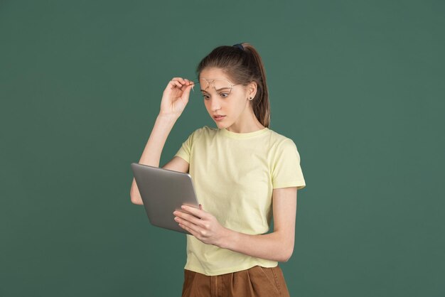 Caucasian young woman's portrait isolated over green studio background with copyspace