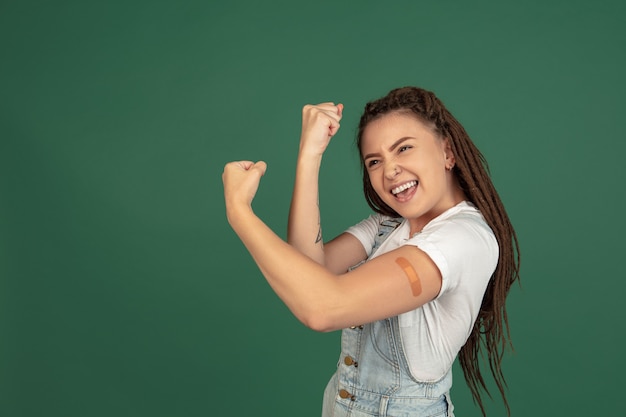 Caucasian young woman's portrait isolated over green studio wall