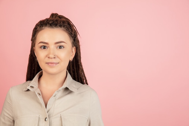 Caucasian young woman's portrait isolated over pink studio wall