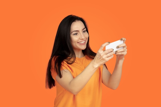 Caucasian young woman's portrait on orange background