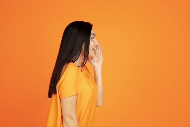 Caucasian young woman's portrait on orange background