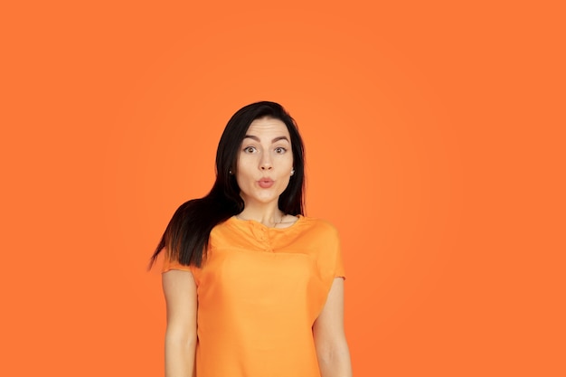 Caucasian young woman's portrait on orange studio