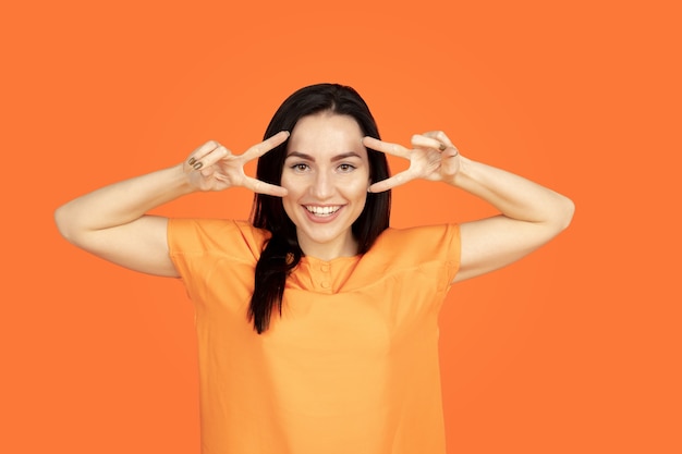 Caucasian young woman's portrait on orange studio