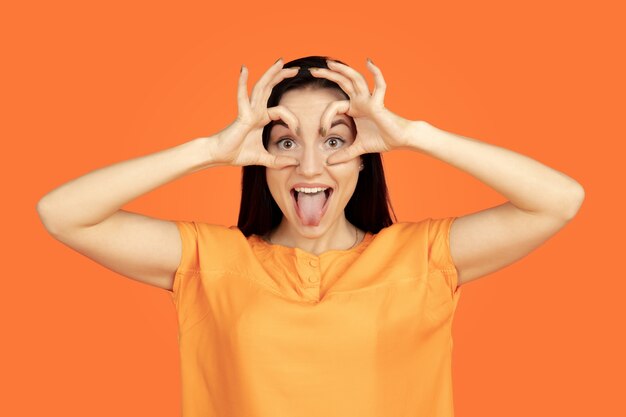 Caucasian young woman's portrait on orange studio