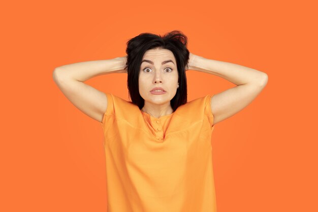 Caucasian young woman's portrait on orange studio