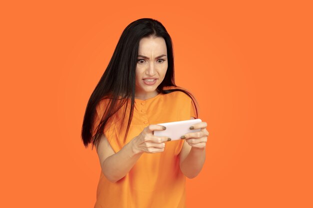 Caucasian young woman's portrait on orange wall