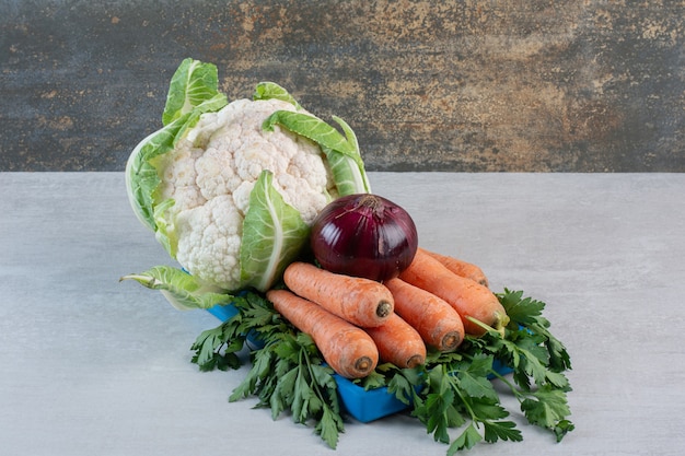 Цветная капуста, морковь и лук на синей тарелке. Фото высокого качества