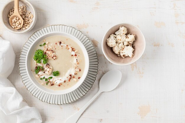 白い背景の鉢に松のナッツを入れたカリフラワークリームスープ