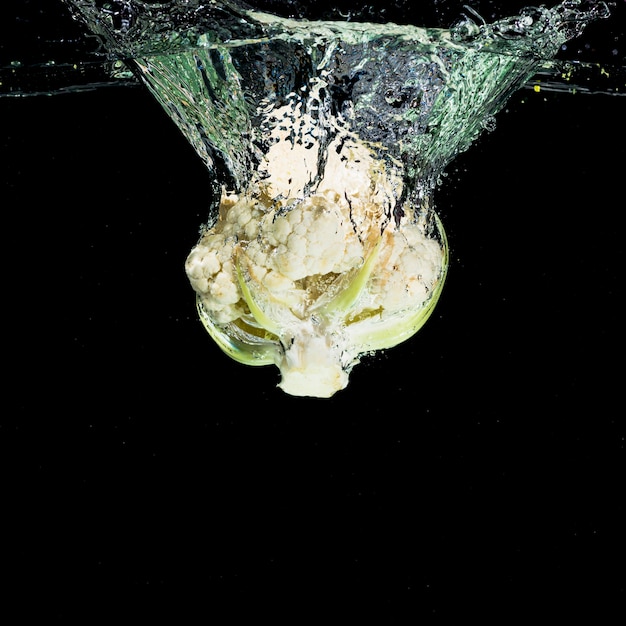 Cauliflower falling into the water against black background