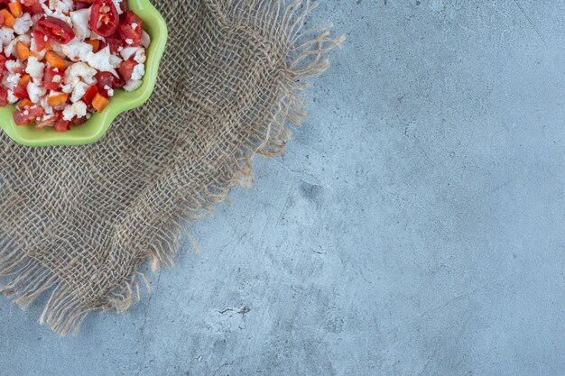 Cauliflower and pepper salad in a green bowl on marble table.