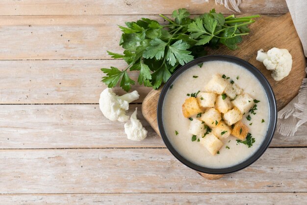 Cauliflower soup in a bowl on wooden table