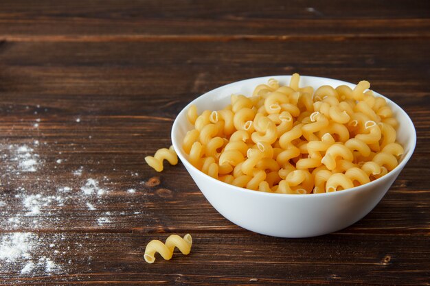 Cavatappi pasta in a bowl on a wooden table. high angle view.