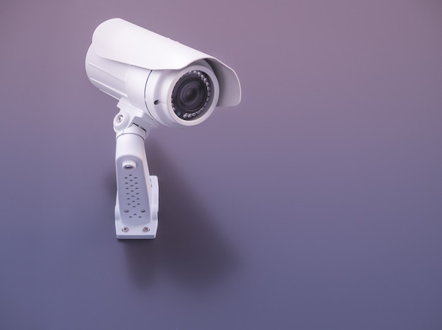 Безопасность камеры видеонаблюдения на фиолетовой стене