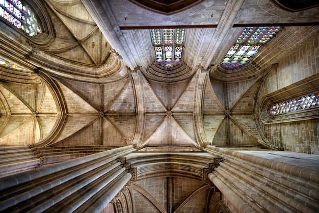 The ceiling in the interior of a historic cathedral with arches and stained glass window