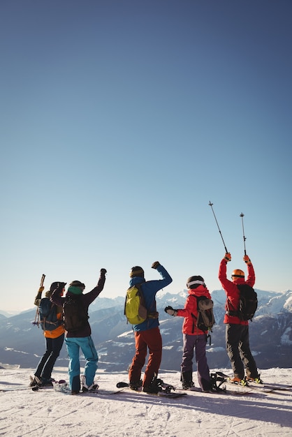 Free photo celebrating skiers standing on snow covered mountain