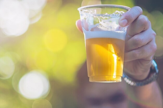 Celebration beer cheers concept - close up hand holding up glasses of beer of man