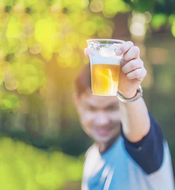 Concetto di acclamazioni della birra di celebrazione - mano alta vicina che sostiene i vetri di birra