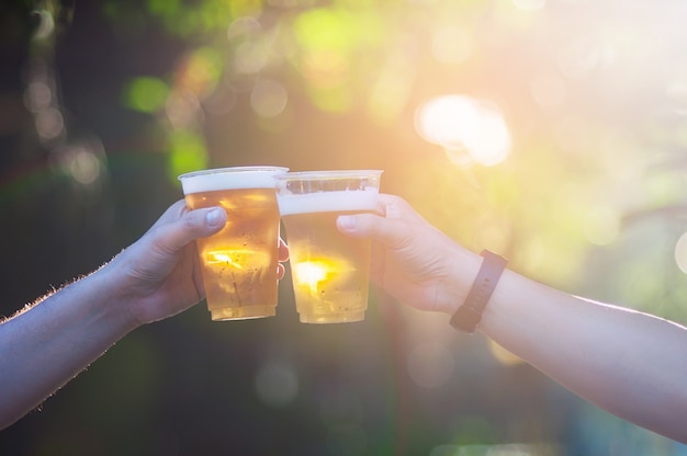 Celebration beer cheers concept - close up hands holding up glasses of beer 