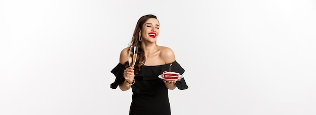 Free photo celebration and party concept fashionable woman holding birthday cake with candle and drinking champ