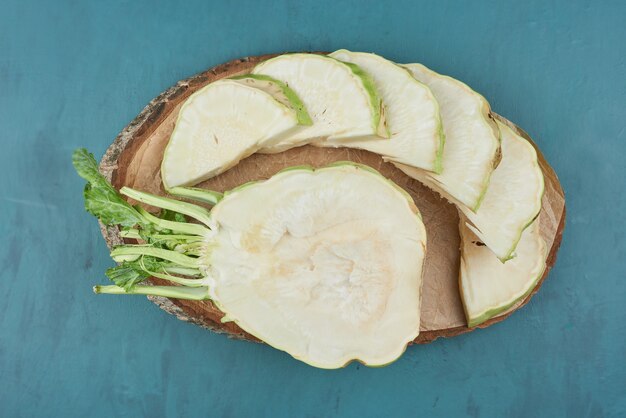 Celery corn on a wooden board on blue .