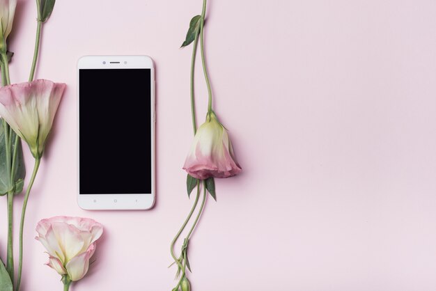 Сотовый телефон с цветами eustoma против розового фона