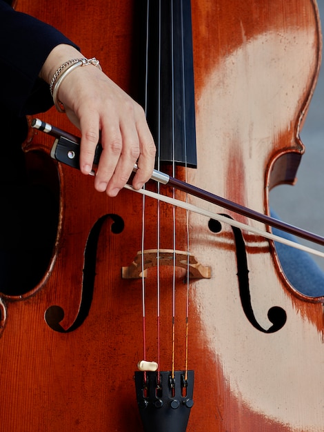 Cellist player hands. Violoncellist playing cello on background of field. Musical art, concept passion in music. Classical music professional cello player solo perform