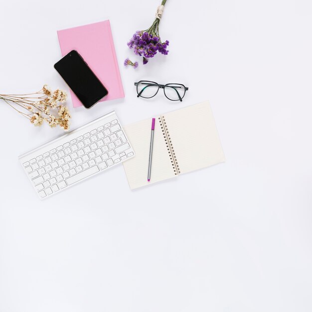 Cellphone; keyboard with stationery and flowers on white background