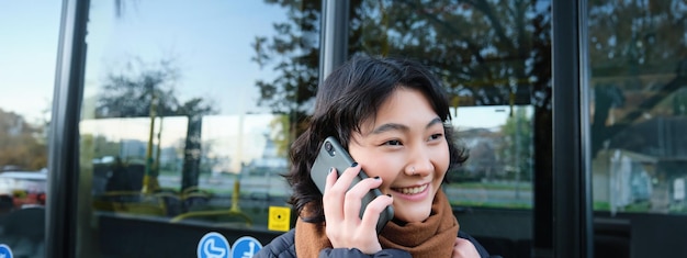 Foto gratuita tecnologia cellulare e concetto di persone una ragazza asiatica alla moda parla al telefono cellulare e fa un telefono