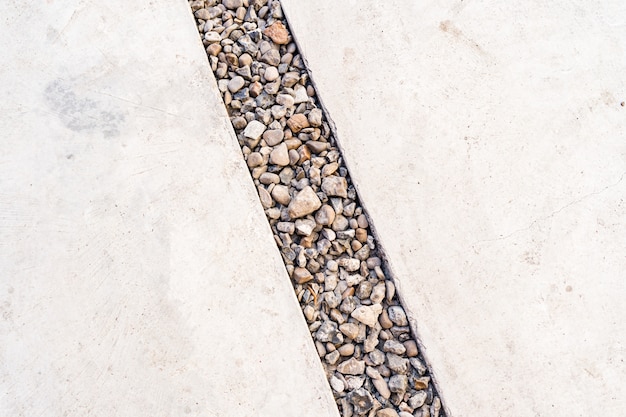 Cement background crossed by a diagonal line of pebbles stone