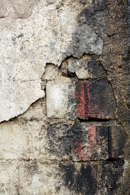 Cement wall with exposed dirty bricks and paint