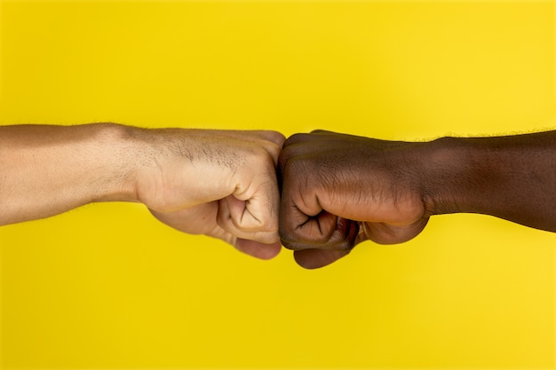 Free photo central view of european and afroamerican hand to hand clenched into fists