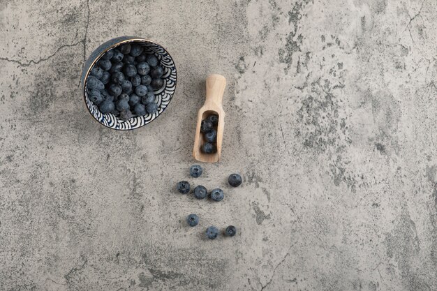 Ceramic bowl of delicious fresh blueberries on marble surface