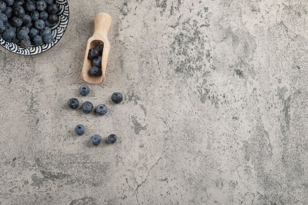 Ceramic bowl of delicious fresh blueberries on marble surface