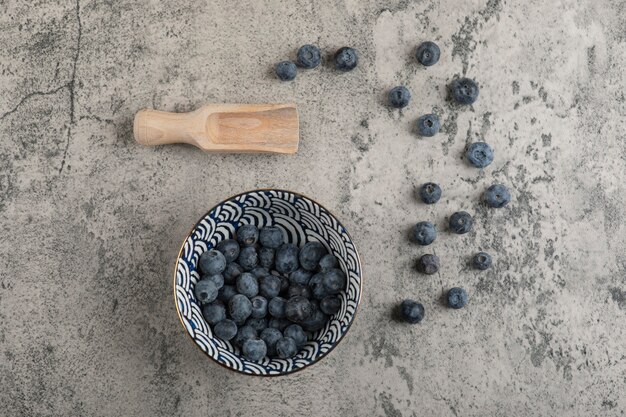Ceramic bowl of delicious fresh blueberries on marble surface