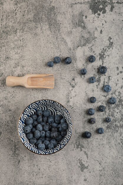 Ceramic bowl of delicious fresh blueberries on marble surface