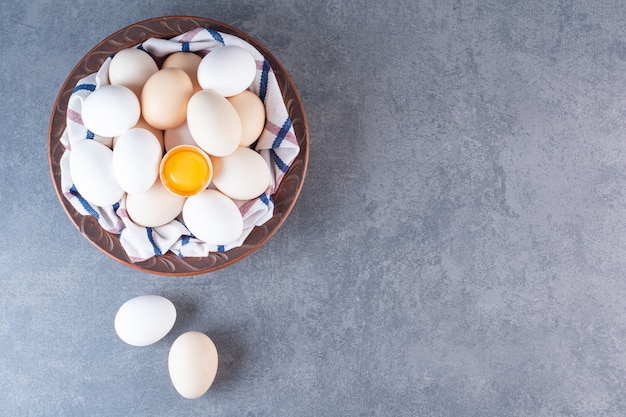 Ceramic bowl full of organic eggs on stone table.