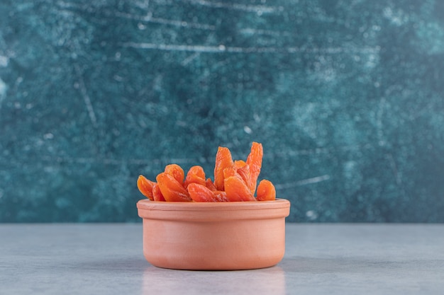 Free photo ceramic bowl with delicious dried fruits on stone background.