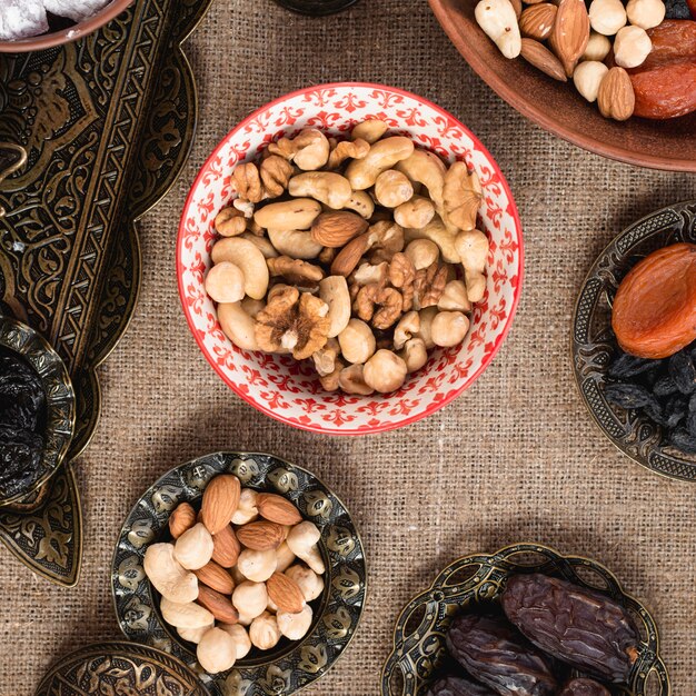 Ceramic and metallic bowl with organic nuts on tablecloth