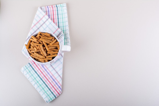 Ceramic mug of tasty crispy crackers on marble background. High quality photo