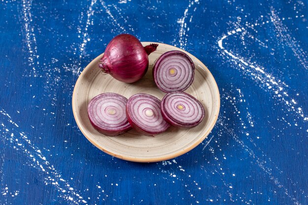 Ceramic plate of purple onion rings on marble surface. 