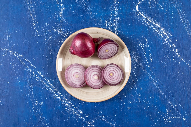 Free photo ceramic plate with purple onion rings on marble surface