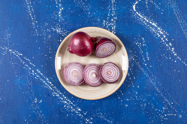 Ceramic plate with purple onion rings on marble surface