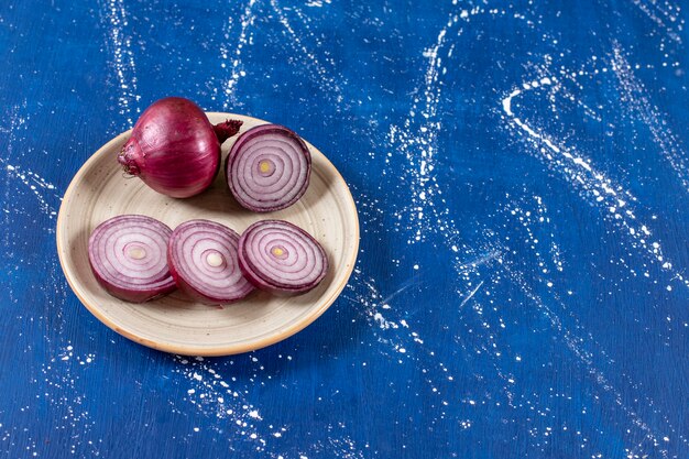 Ceramic plate with purple onion rings on marble surface